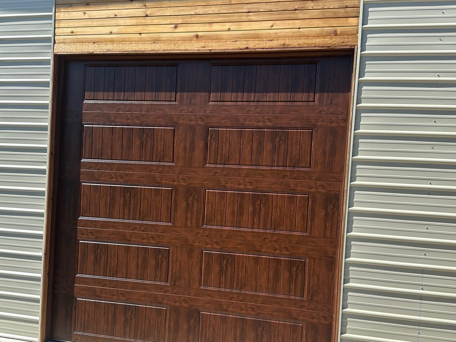 Walnut woodgrain carriage-style garage door on a cream home